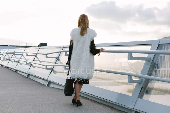 Vue arrière de la femme blonde posant par les mains courantes en ville — Photo de stock