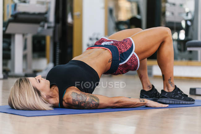 Frau liegt bei Übung auf Teppich — Stockfoto