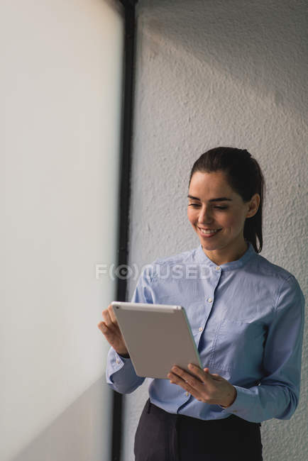 Porträt eines brünetten Mädchens, das in der Nähe des Fensters steht und auf dem Tablet surft — Stockfoto