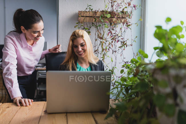 Porträt lächelnder Frauen, die im Büro am Laptop surfen — Stockfoto