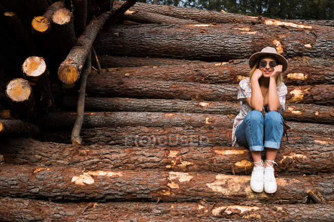 Модна жінка позує на дерев'яних колодах — стокове фото