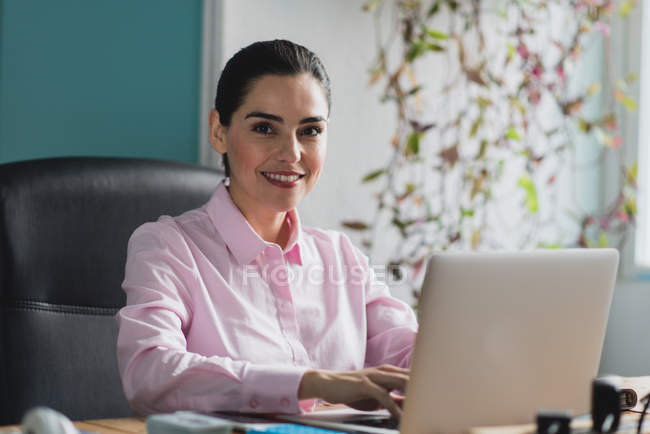 Portrait of smiling woman using  laptop and looking at camera. — Stock Photo