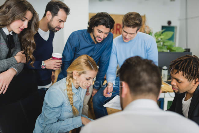 Office team at daily meeting standing and looking down at table — Stock Photo