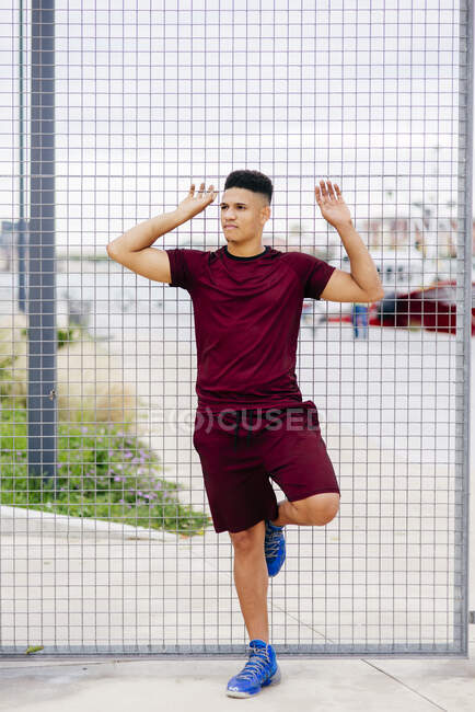 Young sportive man posing on fence — Stock Photo