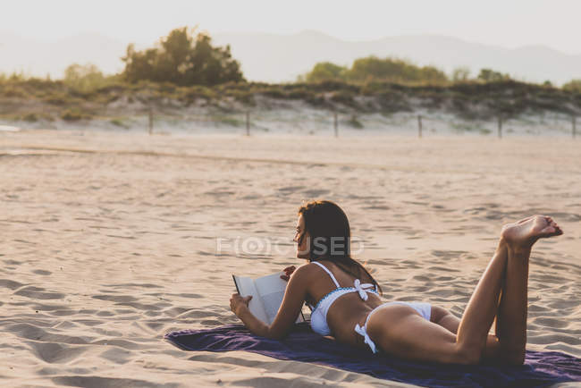 Mujer leyendo libro en la playa - foto de stock