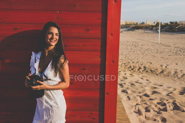 Woman holding a camera at the beach — Stock Photo