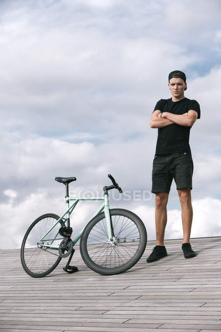 Серьезный мальчик со сложенными руками возле велосипеда — стоковое фото