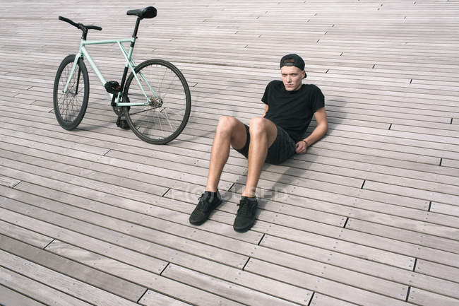 Человек, сидящий рядом со своим велосипедом — стоковое фото