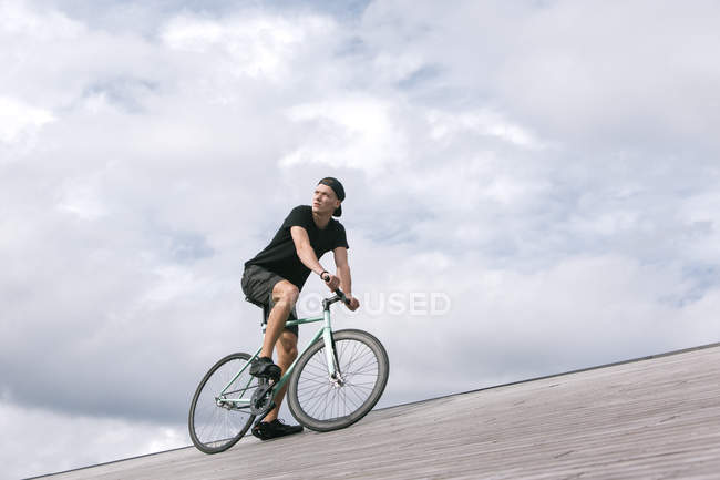 Giovanotto pensieroso in berretto in bicicletta — Foto stock
