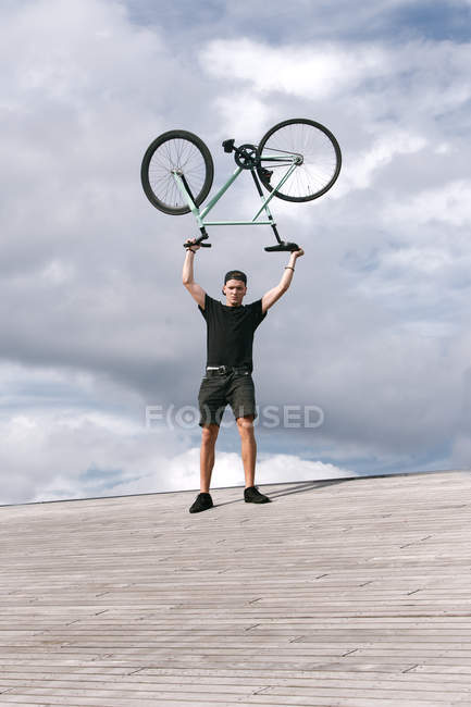 Ragazzo con bici in braccio sopra la testa — Foto stock
