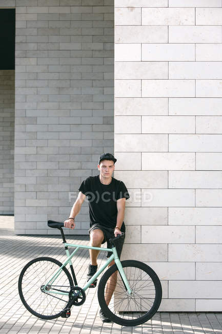 Homem de preto com sua bicicleta — Fotografia de Stock