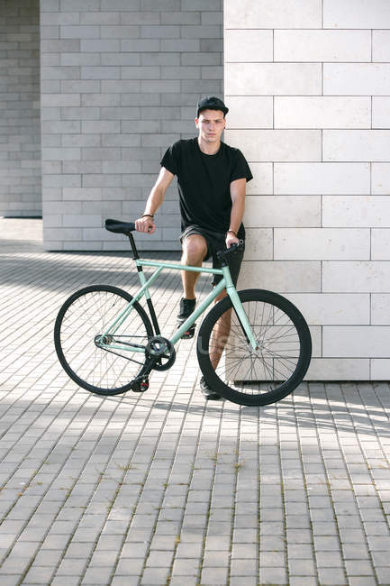 Homem de preto com sua bicicleta — Fotografia de Stock