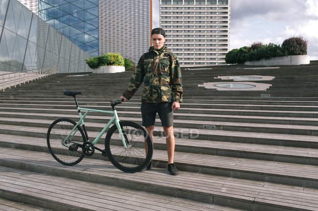 Elegante chico con su bicicleta - foto de stock