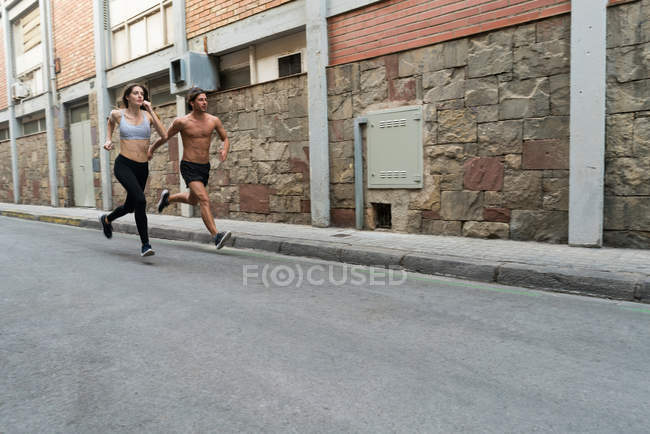 Homme et femme courant dans la rue — Photo de stock