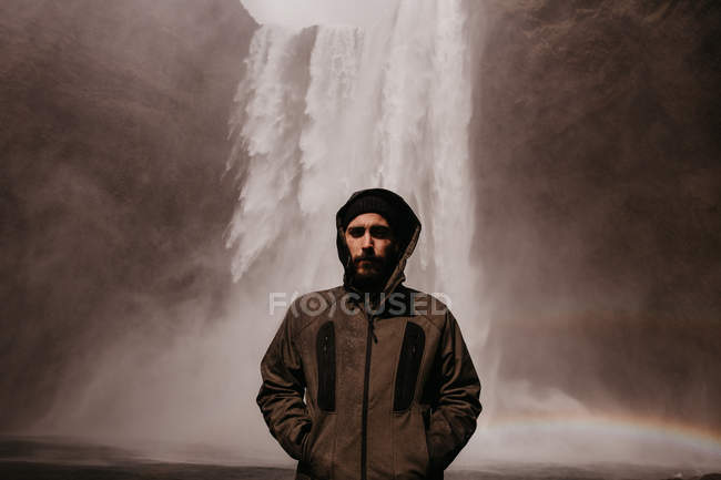 Jeune homme en manteau sur cascade — Photo de stock