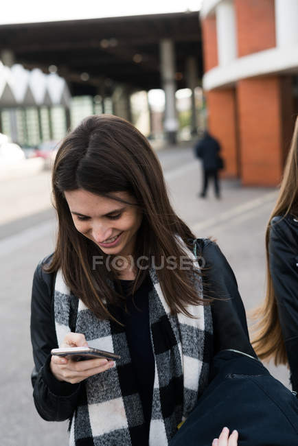 Mulher navegando smartphone durante a caminhada — Fotografia de Stock