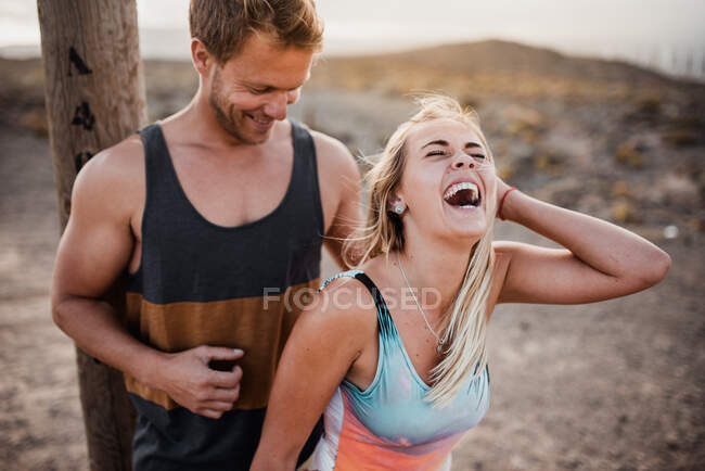 Horizontal ao ar livre tiro de jovem casal de pé e rindo — Fotografia de Stock