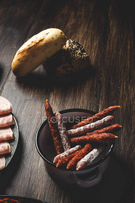 Sauseges and rural bread on wooden table — Stock Photo