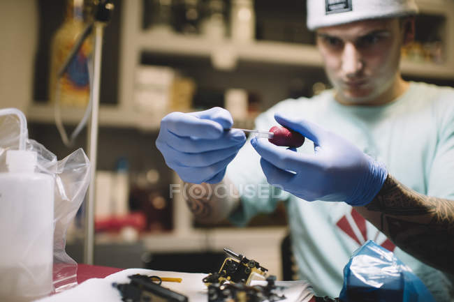 Maestro del tatuaje preparando herramientas y aguja en el lugar de trabajo - foto de stock