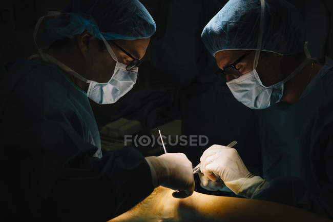 Dos cirujanos con lancetas operando - foto de stock
