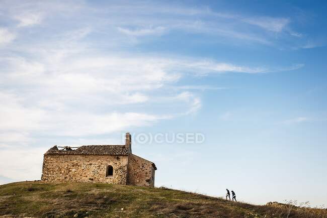 Vue extérieure horizontale du couple marchant vers une vieille maison rustique sur une colline — Photo de stock