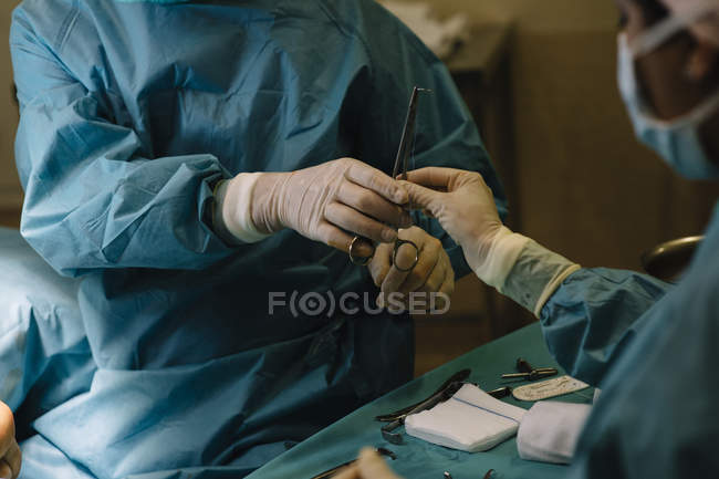 Cirujanos manos tomando herramienta de cirugía - foto de stock