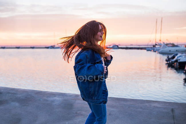 Femme mignonne agitant les cheveux au coucher du soleil — Photo de stock