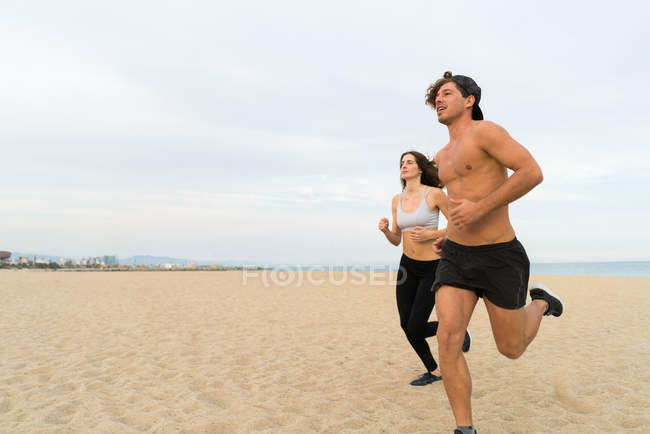 Dos deportistas corriendo en la playa - foto de stock