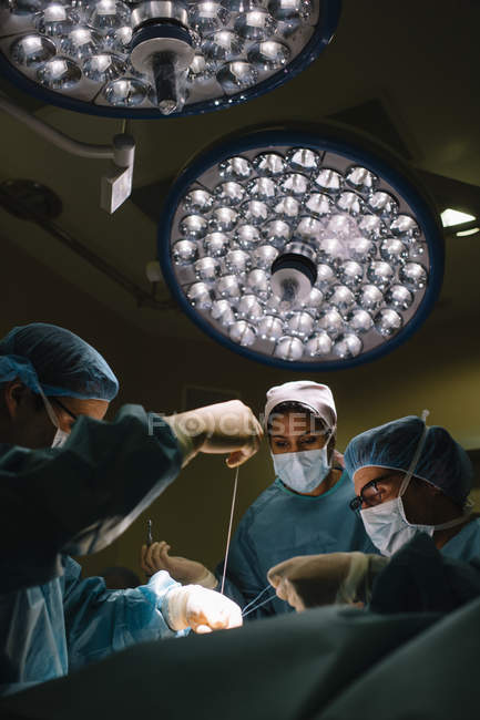 Cirurgiões costurando durante a operação — Fotografia de Stock
