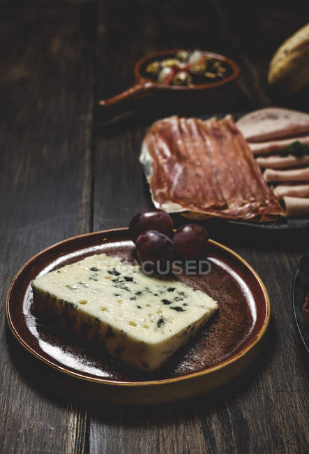 Сыр с виноградом на сельской тарелке — стоковое фото