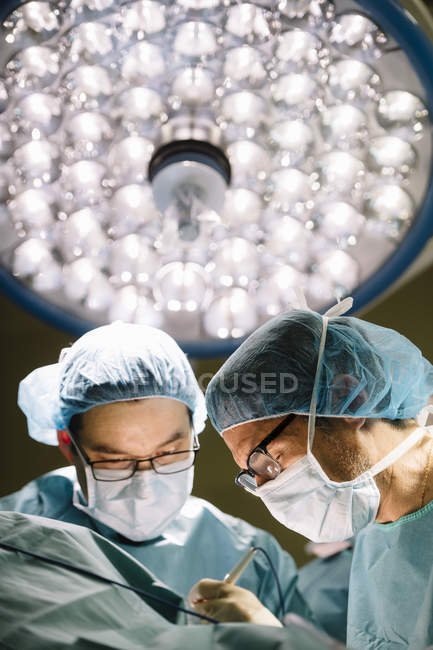 Cirurgiões que operam sob lâmpada — Fotografia de Stock
