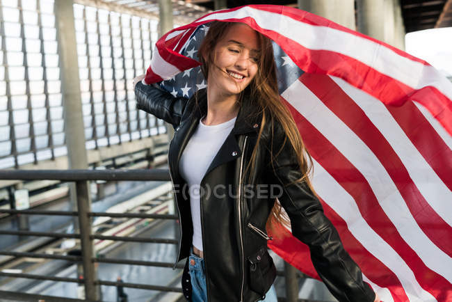 Femme heureuse avec drapeau américain sur la station — Photo de stock