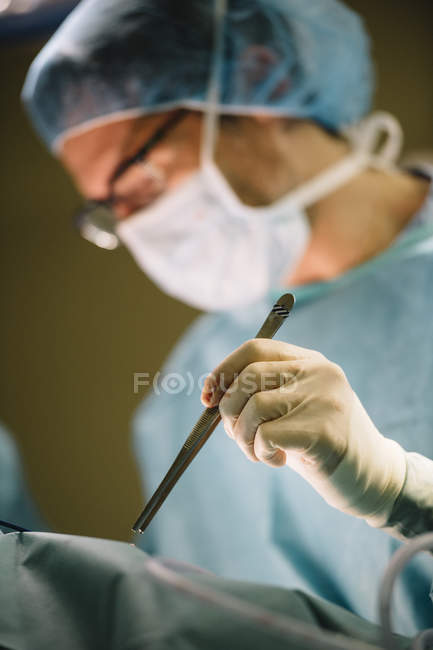 Les chirurgiens mains tenant une pince à épiler — Photo de stock