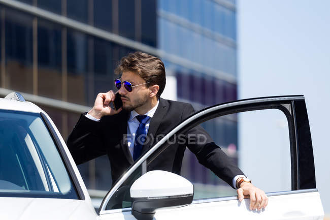 Hombre hablando por teléfono cerca del coche - foto de stock