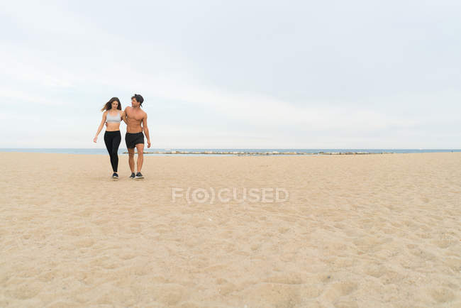 Joven pareja deportiva en la playa - foto de stock