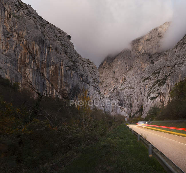 Coche en movimiento en la carretera en las montañas brumosas . - foto de stock