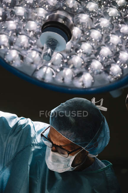 Surgeon in mask standing in lamp light — Stock Photo