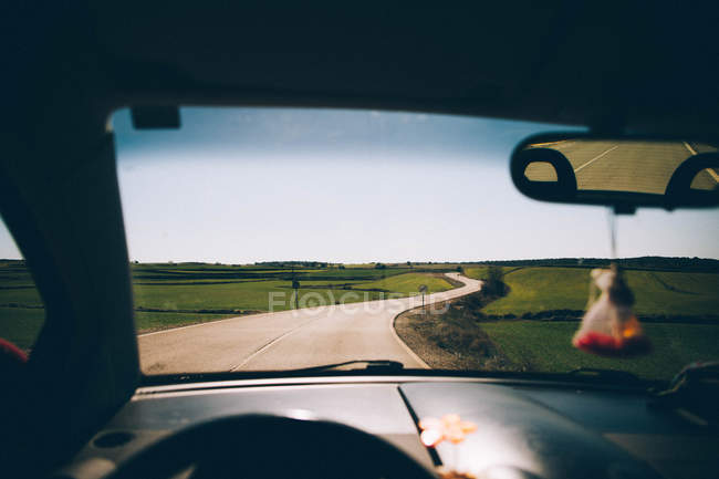 View to empty road through fields seen from car. — Stock Photo