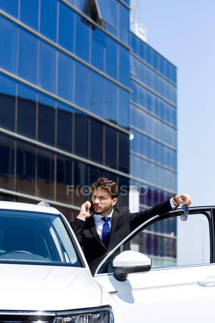 Чоловік розмовляє по телефону біля машини — стокове фото