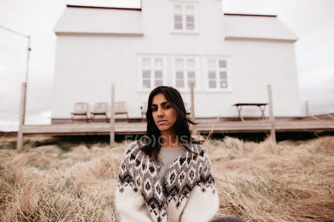 Женщина в тёплом свитере рядом с домом — стоковое фото