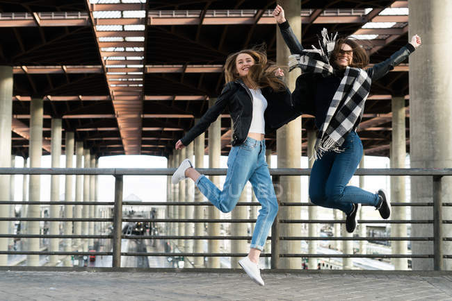 Two pretty girls jumping on station — Stock Photo