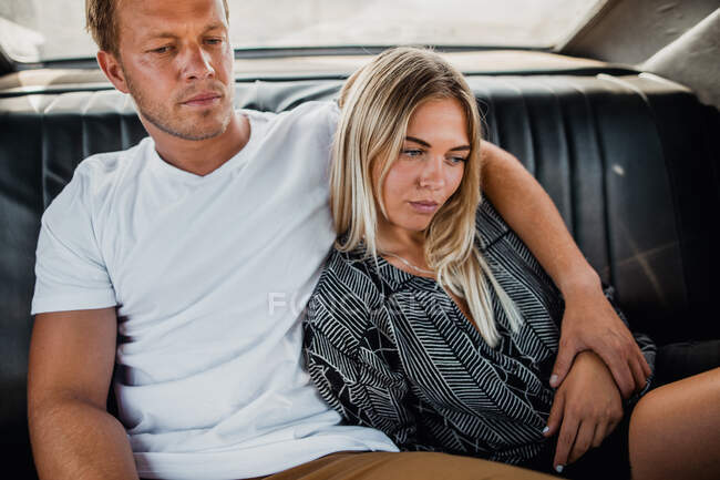 Горизонтальный снимок задумчивой пары, сидящей и обнимающейся в машине — стоковое фото