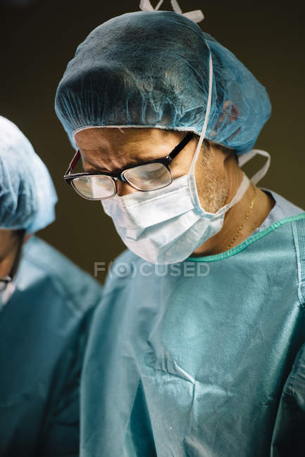 Хирург в маске смотрит вниз — стоковое фото