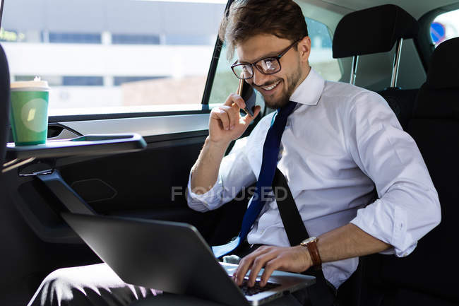 Hombre de negocios con teléfono en coche - foto de stock