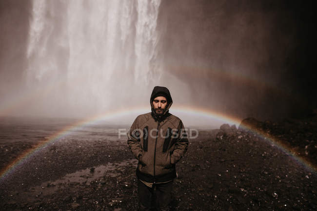 Junger Mann im Mantel am Wasserfall — Stockfoto