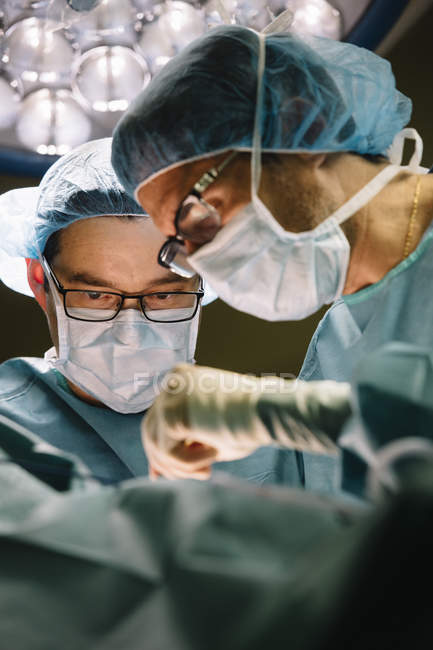Dos cirujanos mientras operaban al paciente - foto de stock