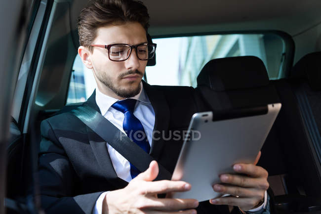 Бизнесмен, использующий планшет в машине — стоковое фото