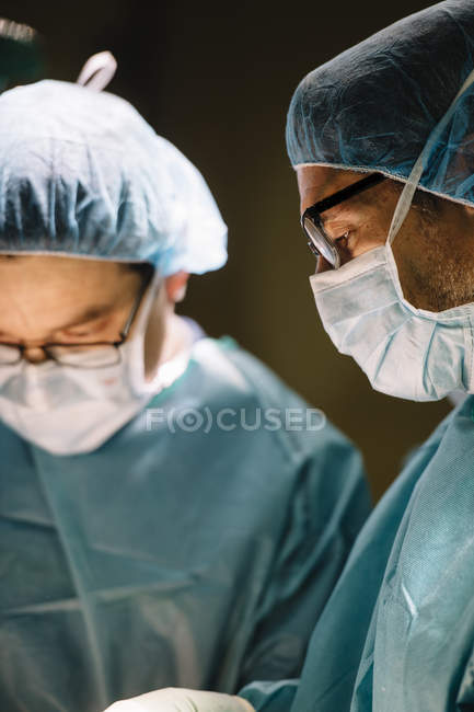 Dos cirujanos mientras operaban al paciente - foto de stock