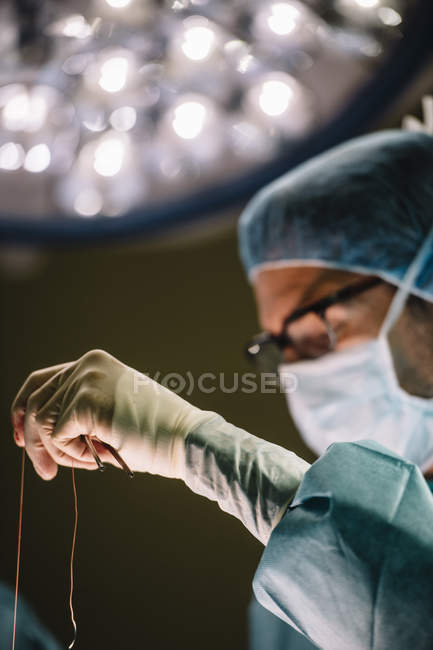 Main de chirurgiens avec aiguille et fil — Photo de stock
