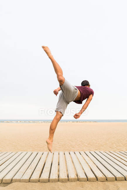 Hombre practicando saltos en la playa - foto de stock